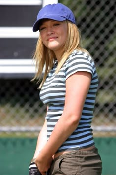 a woman holding a tennis racquet on top of a tennis court with a fence in the background