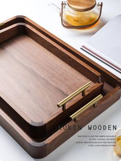 a wooden tray with gold handles on top of a white table next to some glasses