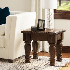 a living room with a white couch and wooden table in front of a window on top of a rug