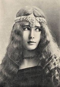 an old black and white photo of a woman with long hair wearing a headband