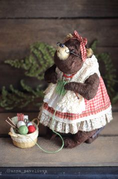 a brown teddy bear wearing a dress and glasses next to a basket with eggs in it