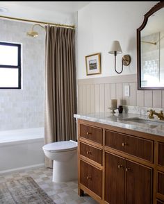 a white toilet sitting next to a bath tub in a bathroom under a window with curtains