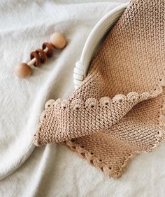 a close up of a knitted object on a bed next to beads and wood