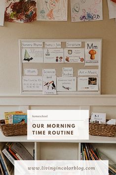 a shelf with books and pictures hanging on the wall next to a basket filled with children's artwork