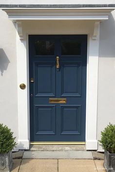 a blue front door with two planters on either side and one potted plant