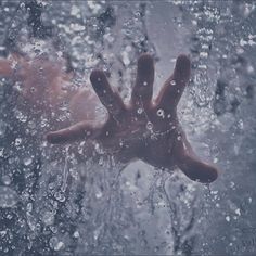 a person's hand sticking out of a window covered in rain drops and water