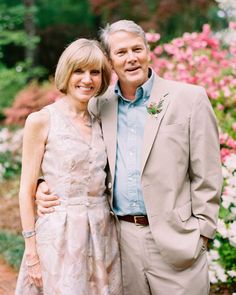 a man and woman standing next to each other in front of flowers