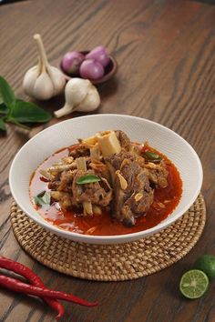 a white bowl filled with food on top of a wooden table next to red peppers