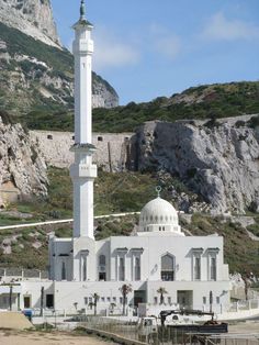 a large white building with a tall tower on top of it's side next to a mountain