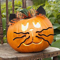 a pumpkin with a cat's face carved into it, sitting on a bench