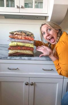 a woman standing in front of a stack of food on top of a stovetop