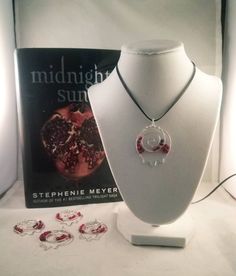 the necklace is on display next to other jewelry items and a book that reads midnight sun