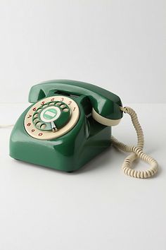 an old - fashioned green phone is sitting on the table with its cord still attached