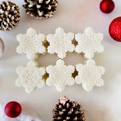 snowflakes and pine cones are arranged on a white surface next to christmas ornaments