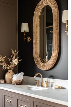 a bathroom vanity with two sinks and a large oval mirror above it, along with a gold faucet