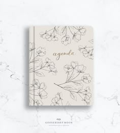 the agenda book with flowers and leaves on it, sitting on top of a marble surface