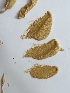 three different shades of foundation on a white surface, one is yellow and the other is brown