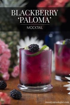 two glasses filled with blackberry lemonade and blackberries on top of a wooden table