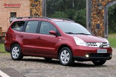 a small red car parked in front of a brick building on a cobblestone road