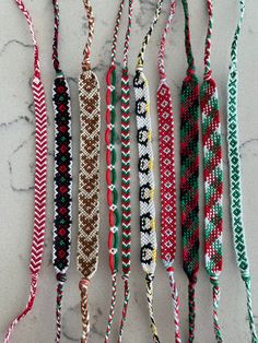 several different colored bracelets hanging on a marble counter top with white and red beads