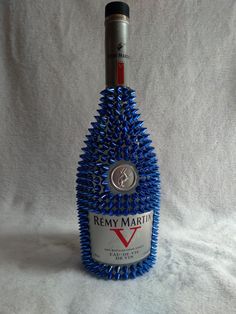 a bottle of wine that is sitting on a white surface with blue spiky hair