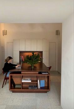 a woman sitting at a table in front of a book shelf