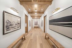 a long hallway with wooden benches and paintings on the wall