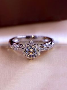 a diamond ring sitting on top of a white cloth covered table next to a mirror