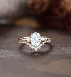 a close up of a diamond ring on a wooden table with roses in the background