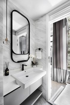 a bathroom with marble walls and flooring, white countertops and black framed mirror on the wall