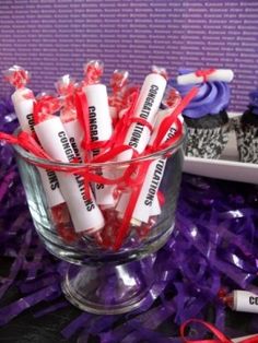 a glass bowl filled with red and white candies on top of purple streamers