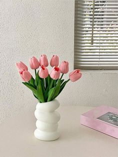 pink tulips in a white vase on a table