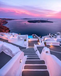 the stairs lead up to an outdoor swimming pool at dusk, overlooking the ocean and cliffs