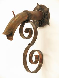 a metal hook with a cat on it's head hanging from the side of a wall