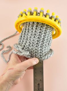 a person holding a measuring tape and a knitted object