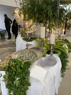 a table topped with lots of plants and candles