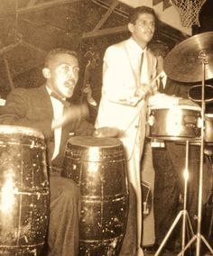 two men in suits are playing music on drums