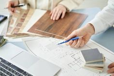 two people are working on some wood flooring and one person is using a laptop