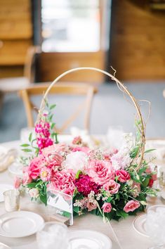 a table set with plates and flowers in a basket on top of the table for a wedding reception