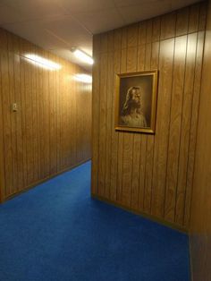 an empty room with wooden walls and blue carpet