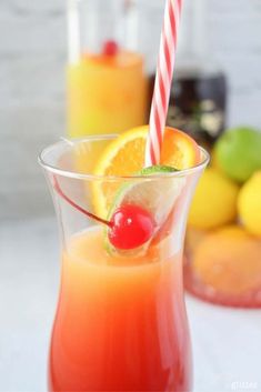 a glass filled with orange juice and topped with a cherry