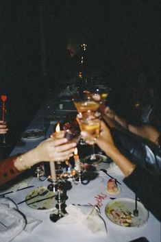 several people are toasting at a long table with food and drinks in front of them