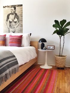 a bed room with a neatly made bed and a potted plant