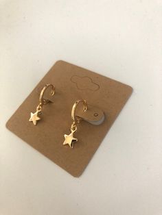 Small gold huggie hoops with dangling star charm. Lever back closure. 18K plated gold helps reduce sensitivity and make them hypoallergenic. Very lightweight style of earring that does not pull on ears at all. Simple style goes with every outfit! Cute Hoops Earrings, Gold Huggie Earrings With Charm, Dangly Gold Earrings, Gold Jewellery Earrings, Gold Piercings, Small Gold Earrings, Earrings Huggies, Gold Star Earrings, Dainty Gold Earrings