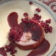 a white plate topped with food covered in sauce and pomegranates