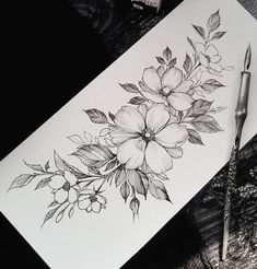 some flowers are on top of a piece of paper next to a pen and ink