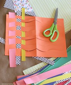 scissors are sitting on top of some cut out pieces of paper and strips of construction paper