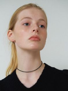 a woman with blonde hair wearing a black sweater and a choker on her neck