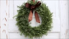 a wreath hanging on the side of a white door with a brown ribbon and bow