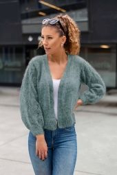 a woman standing on the sidewalk wearing jeans and a sweater